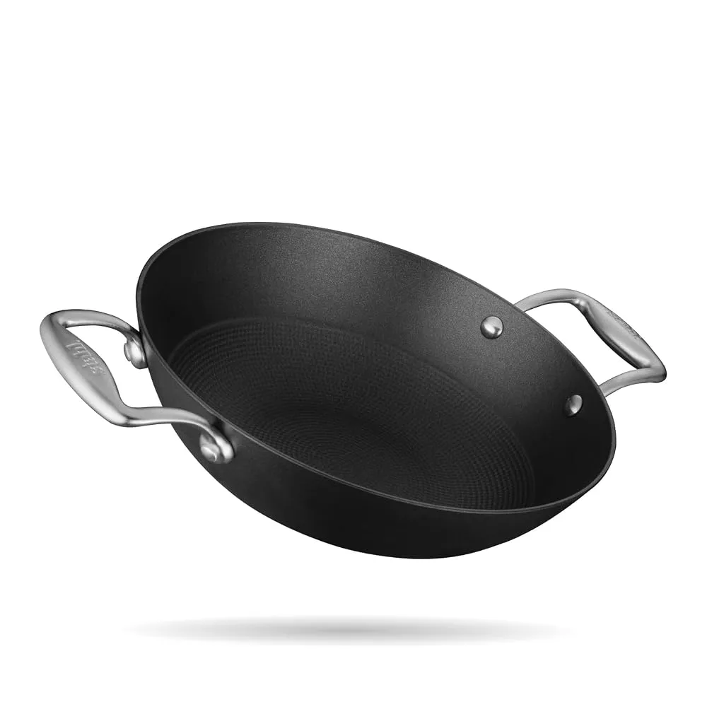 A collection of seasoned cast iron kadhai and tawa on a modern kitchen counter