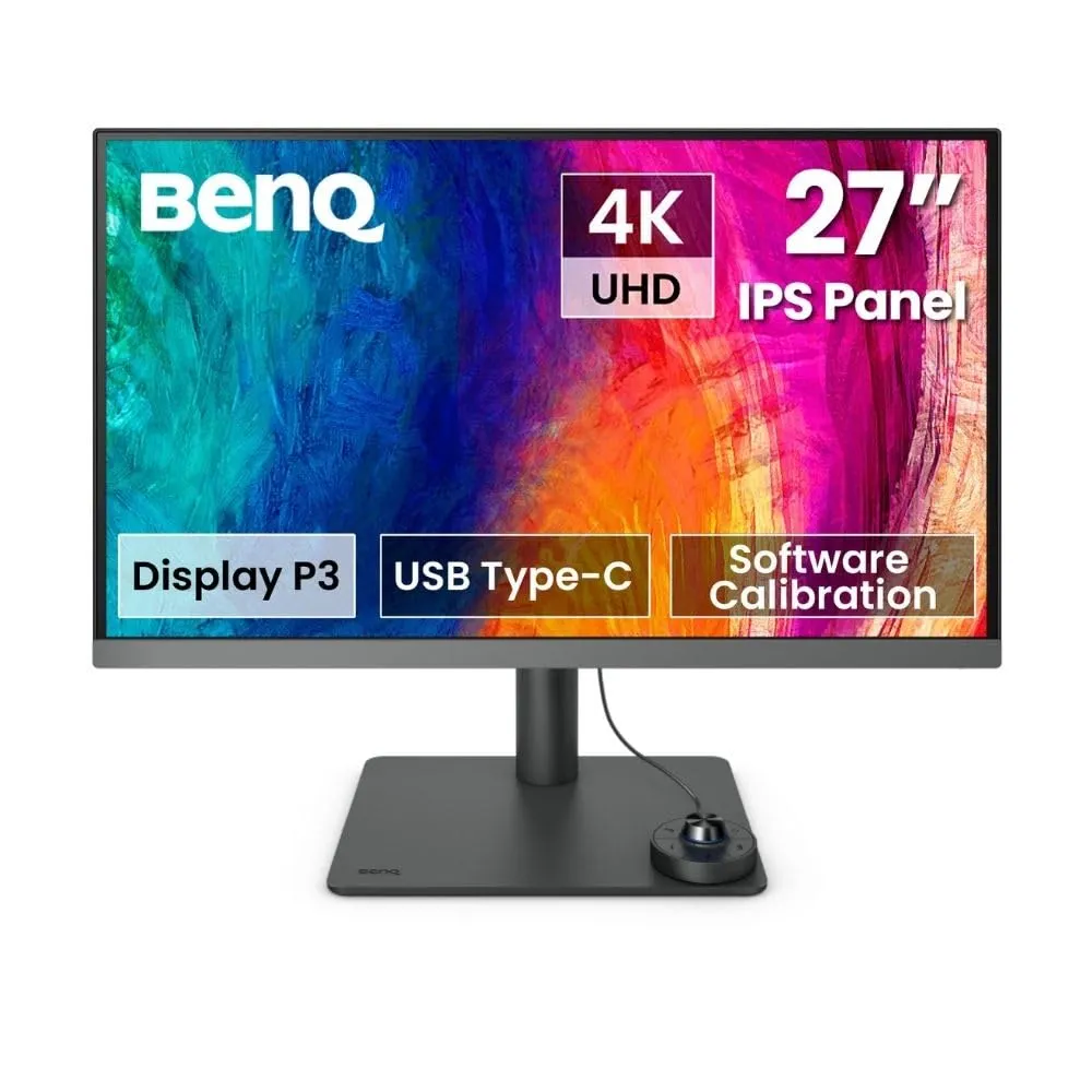A high-end professional monitor setup on a clean desk with a laptop and design tools.