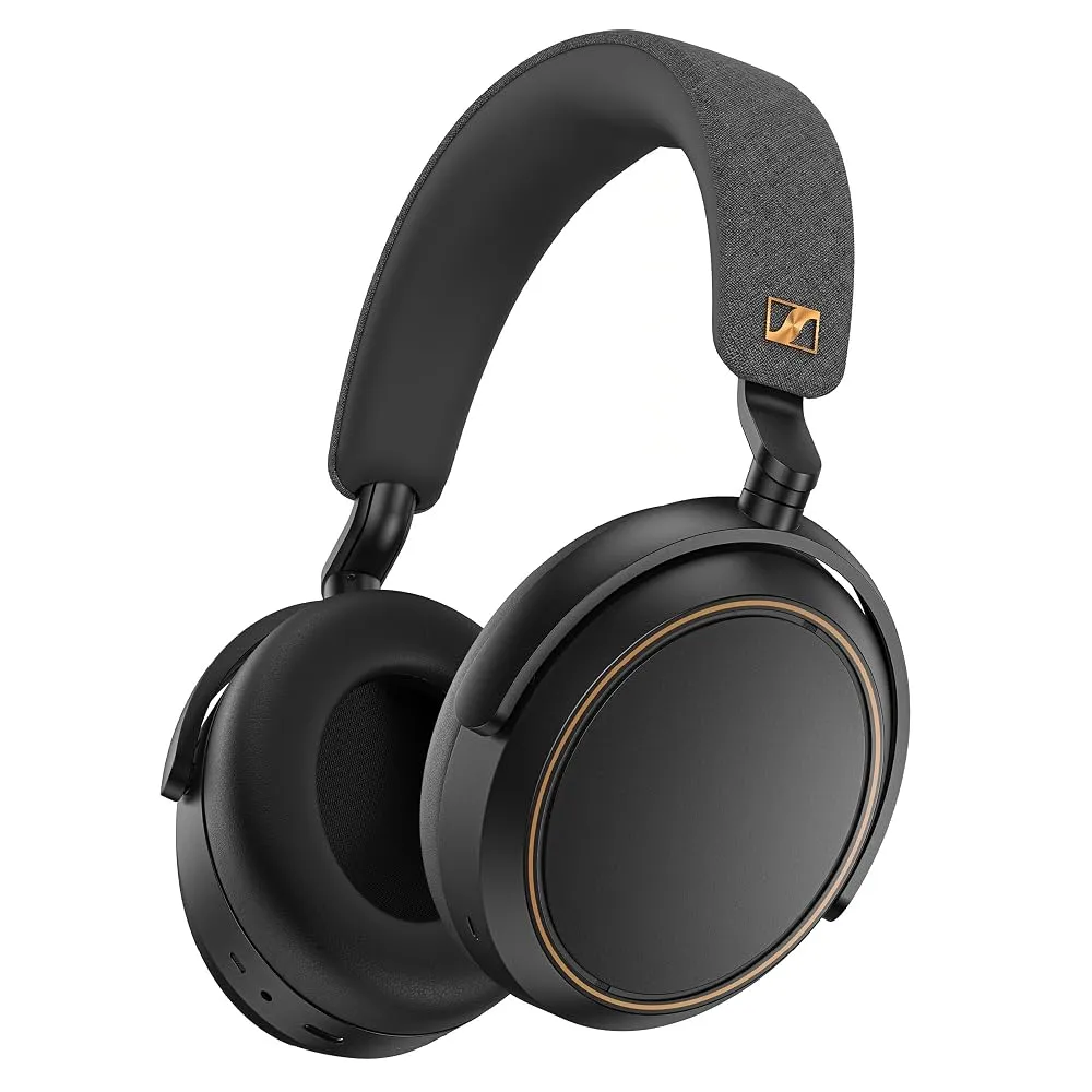 A pair of premium over-the-ear wireless headphones resting on a wooden desk next to a smartphone.