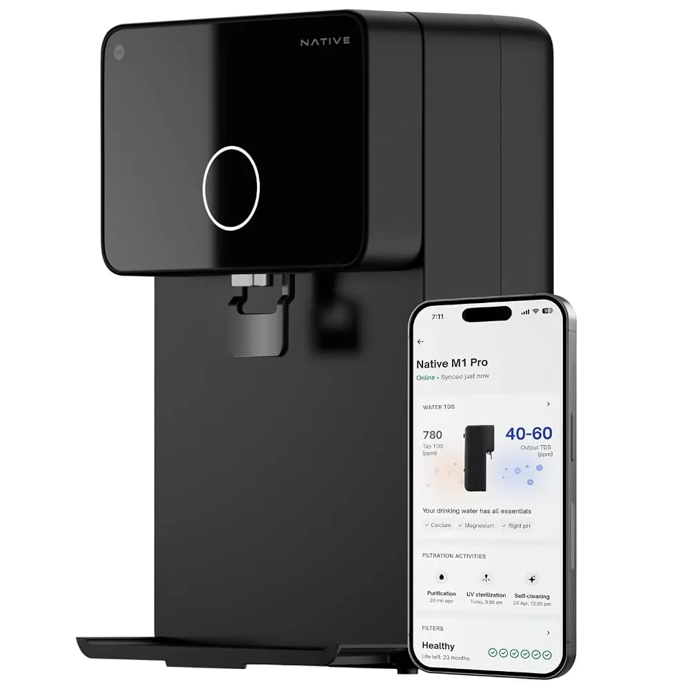 A modern kitchen water purifier mounted on a wall dispensing clean drinking water into a glass